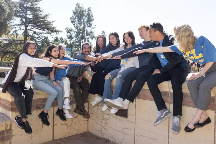 The DCP team sitting on a wall with their hands outstretched toward the middle