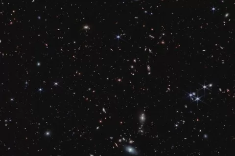  More than 20,000 tiny galaxies appear across the black background of space.